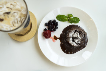 Chocolate lava cake with iced coffee on white plate