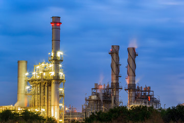 Gas turbine electrical power plant with orange sky and steam from cooling tower.
