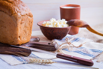 Cottage cheese, a cup of milk and bread on old wooden table. Country style