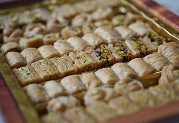 Macro detail of typical Arabian sweets(asabe, balluriah, eschkajoo, turkiya) set in rows of different kinds of eastern pastry 