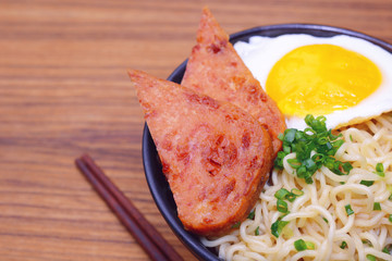 soup noodle mixed with deep fried pork meat, egg, green spring onion served on bowl.