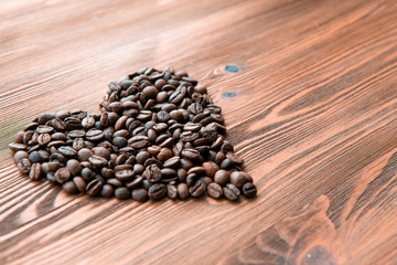 Heart symbol, roasted coffee beans in rustic wooden background.