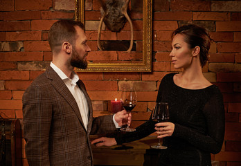 Well-dressed couple with glass of red wine in cozy home interior