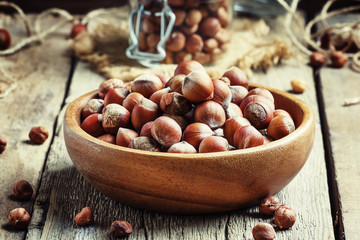 Raw hazelnuts in shell in a bowl on the old wooden background, s