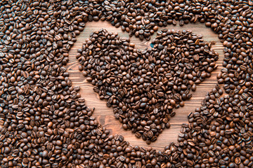 Heart shape created with coffee beans on a wooden background