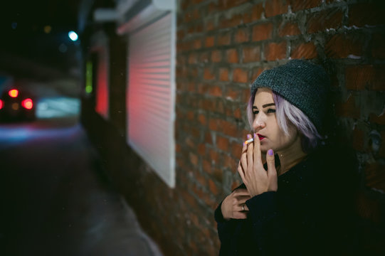 Portrait of a girl with a cigarette. young beautiful girl with dyed hair hipster hat. cigarette smoking on the street under the snow