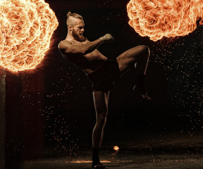 Professional fighter shadowboxing with fire and sparks on background