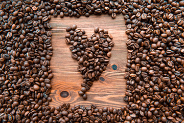Heart symbol, roasted coffee beans in rustic wooden background.