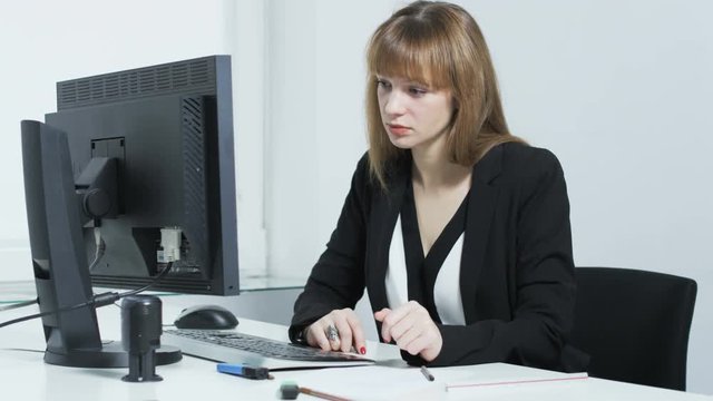 Pretty young woman bored while looking at a computer