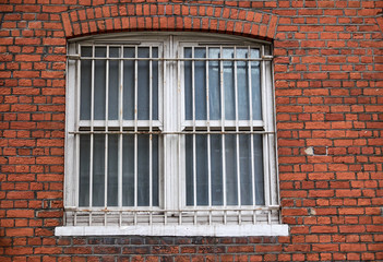 Window with security bars of metal in a red brick building facade