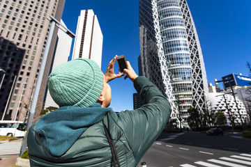 A tourist taking picture by phone of business architecture in Tokyo, Japan