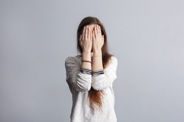 Girl with long hair covers his face with his hands.  - obrazy, fototapety, plakaty