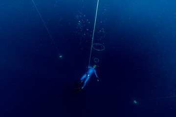 Obraz na płótnie Canvas Free diver making air bubbles ring deep underwater
