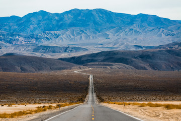 Road in the Death Valley National Park with mountains on the horizon. USA - obrazy, fototapety, plakaty