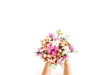 Girl's hands holding wildflowers bouquet on white background. Flat lay, top view