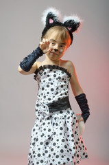 Attractive little girl dressed as a cat on a gray background.
