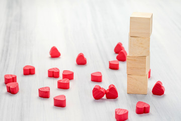 Stack of blank wood cube with group of mini red heart on white r