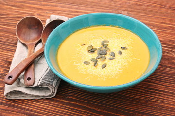Pumpkin and carrot soup with cream and parsley on dark wooden ba