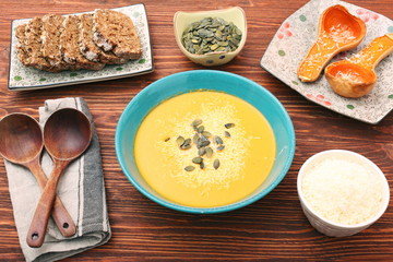Pumpkin and carrot soup with cream and parsley on dark wooden ba