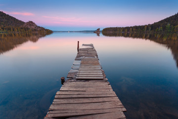 Wooden pier on a blue lake sunset and smooth reflection on water. Long exposure; Borovoye Lake; Kazakhstan.