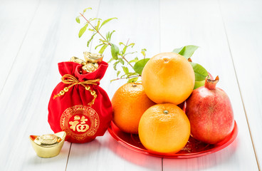 Chinese New year,red felt fabric bag with gold ingots and oranges and flower on white wood table top,Chinese Language mean Happiness.