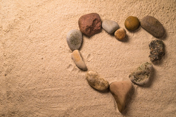 Fototapeta na wymiar Heart arranged with stones on the sand 