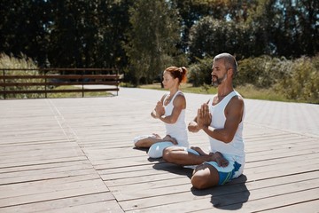 Acro yoga, two sporty people practice yoga in pair, couple doing stretching exercise in the park