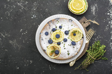 Comfort food. Homemade flavored sponge cake with blueberries and slices of lemon on a marble background. Top
