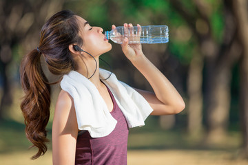 Asian young woman drinking water after jogging