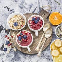 Healthy breakfast. Blueberry banana smoothie in a la carte dishes with granola and pomegranate on  marble background. selective focus