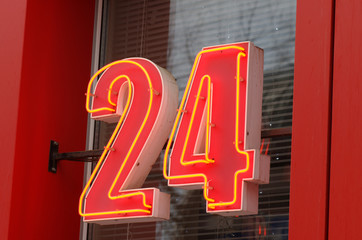 A closeup to a bright neon 24 sign. Photo taken at cloudy day.