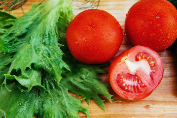 Ripe red tomatoes and knife on cutting board