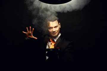 Young brunette magician in costume performing flame tricks