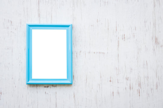 Blue photo frame over white rustic wooden background