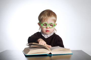 boy in funny glasses reading book on white