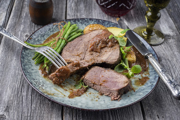 Aufgeschnittener Hirschbraten mit Gemüse und Kartoffel in Burgundersauce auf Teller