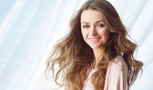 Happy woman on the beach. Portrait of the beautiful girl close-up, the wind fluttering hair. Spring portrait on the beach. Young pretty girl. young smiling woman outdoors portrait. Close portrait.