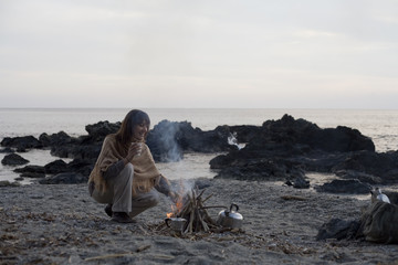 femme souriante sur la plage au coin du feu en hiver
