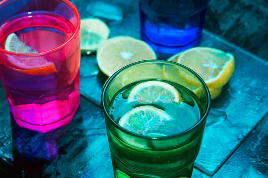 Sparkling water, soda or a gin and tonic in colorful glasses with lemon and ice.Concept for bar menu or detox  with water with lemon.