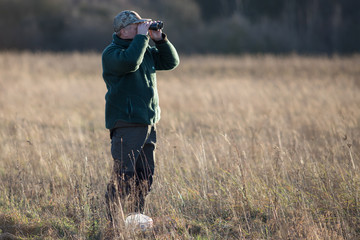 Ein Jäger beobachtet sein Revier mit dem Fernglas/ A hunter observes his Fields with a binoculars
