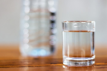 Drinking water in glass and plastic bottles on a wooden table.