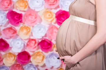 pregnant woman's belly over colorful flowers background