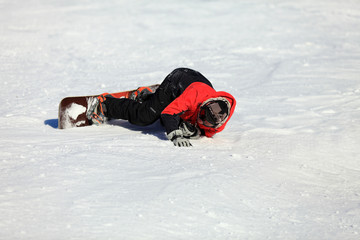 Dorosły mężczyzna leży na śniegu z deską snowboardową. - obrazy, fototapety, plakaty