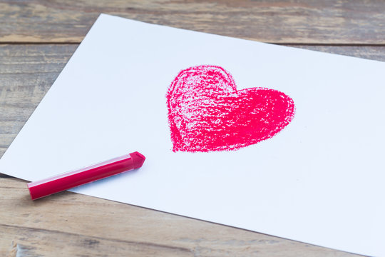 Red heart of crayon on white paper