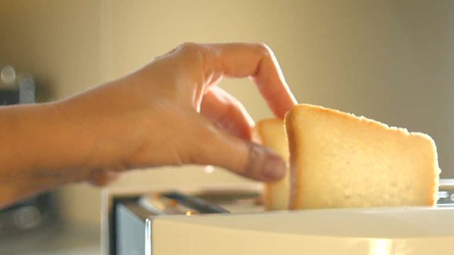 Woman's hand putting two pieces of bread in toaster machine. 4K ultra high definition video. UHD 3840X2160