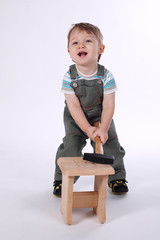 little boy with hammer and wooden chair