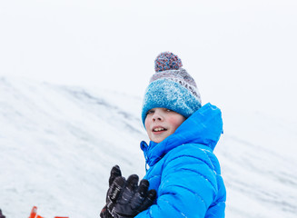 Fototapeta na wymiar Portrait of joyful boy on a frozen snowy slope..