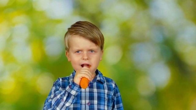 Cute little boy eating carrot and smiling