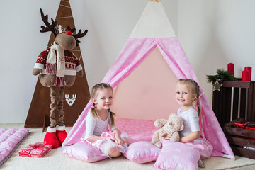 Two little girls play in a teepee