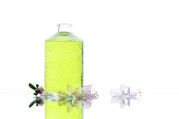 Glass bottle with green liquid and flowers